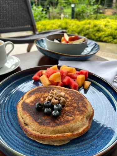un piatto blu con pancake e frutta su un tavolo di Vera Eco-Resort a Santa Emilia
