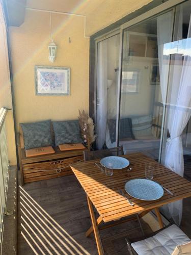 d'une terrasse avec une table en bois et un canapé. dans l'établissement Fleur Australe, à Gruissan