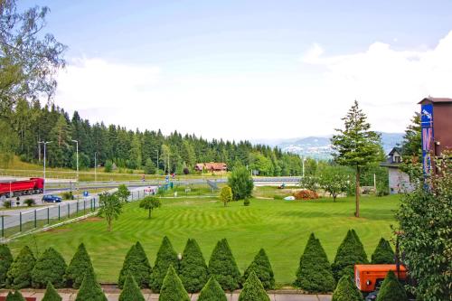 a park with a green lawn and trees next to a road at Motel Na Zbójeckiej in Skawa