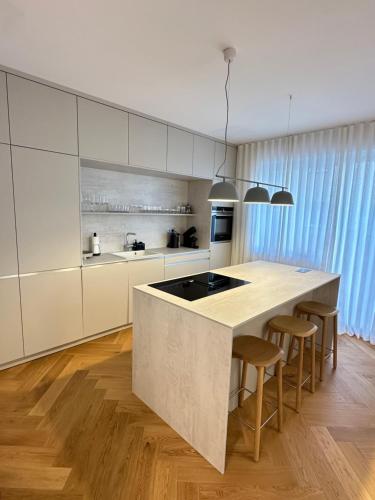 a kitchen with white cabinets and a island with bar stools at Bratislava OLDTOWN Apartment 130m2 ,60m2 terrace and 2 bathrooms in Bratislava