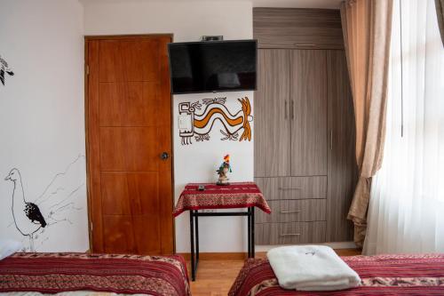 a room with a table and a television on a wall at Casa Antade Cusco in Cusco