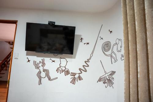 a wall with a tv and some drawings on it at Casa Antade Cusco in Cusco