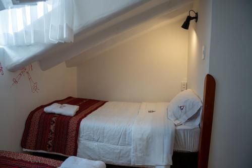 a small bedroom with a bed and a staircase at Casa Antade Cusco in Cusco