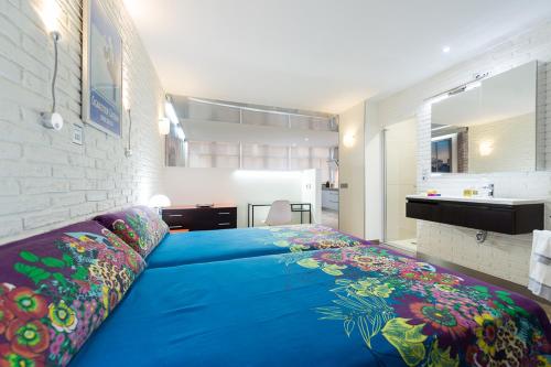 a large blue bed in a room with a bathroom at Suites Garden Loft Dalí in Las Palmas de Gran Canaria