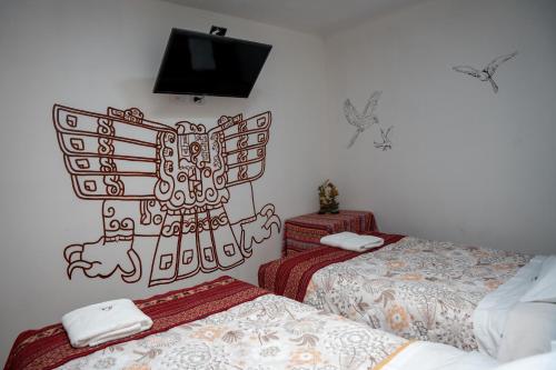 a room with two beds and a tv on the wall at Casa Antade Cusco in Cusco