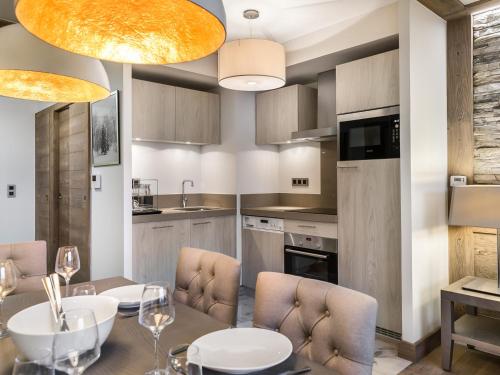 - une cuisine avec une table à manger et des chaises dans l'établissement Appartement élégant avec accès facile aux pistes, parking et salle de fitness - FR-1-562-23, à Courchevel