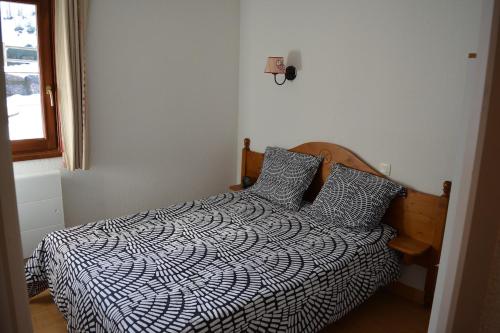 une chambre avec un lit avec une couette noire et blanche dans l'établissement Appartement 4 Personnes - Flumet - Espace Diamant - avec piscine chauffée, à Flumet