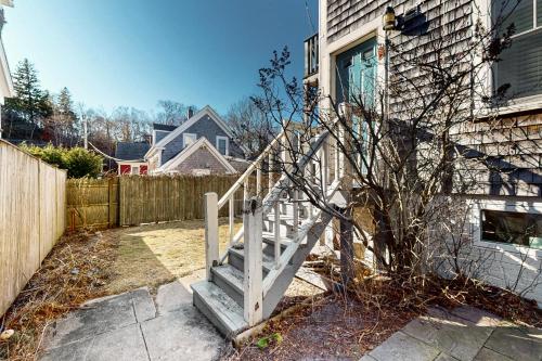 a house with a white staircase next to a fence at Standish Place in Provincetown
