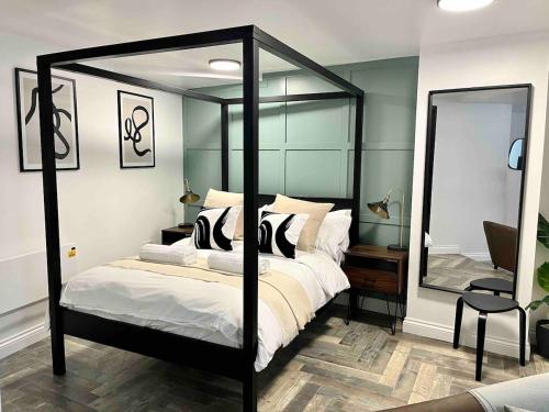トーキーにあるStylish Studio Apartment on Torquay Harbourside!のベッドルーム(鏡付きの黒い天蓋付きベッド1台付)