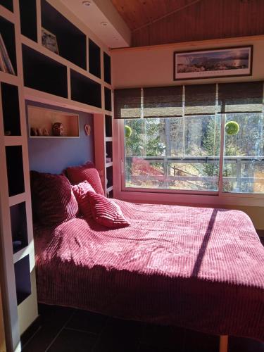 une chambre avec un lit avec une couette rouge et une fenêtre dans l'établissement chalet LES GRANDES TERRES, à Enchastrayes