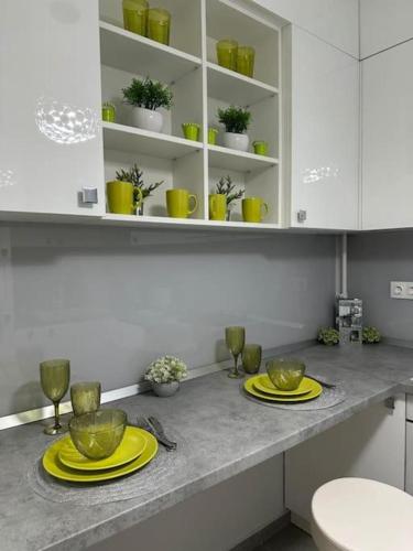 a kitchen counter with yellow plates and glasses on it at Verdana apartament in Timişoara