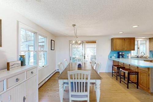 a kitchen with a wooden table and white chairs at National Seashore Retreat in Eastham