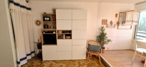 - un salon avec une armoire blanche et une chaise dans l'établissement Studio 4 pers, cosy ,3mn mer, parking, à La Grande Motte