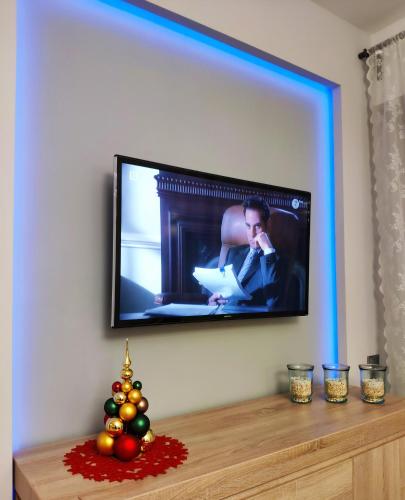 a flat screen tv hanging on a wall with a christmas tree at Wzgórze Słońca in Gródek Nad Dunajcem
