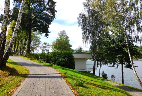 a walkway next to a lake with trees at Wzgórze Słońca in Gródek Nad Dunajcem