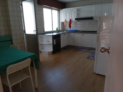 a kitchen with white cabinets and a green table at Paseo de noia in Noya