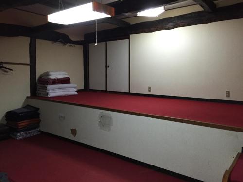 a room with a red floor and white walls at Ichinokurasou in Hakuba