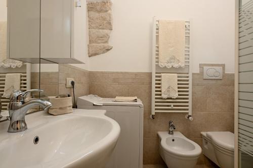 a white bathroom with a sink and a toilet at Pietra e Sogni Coppia in Alberobello