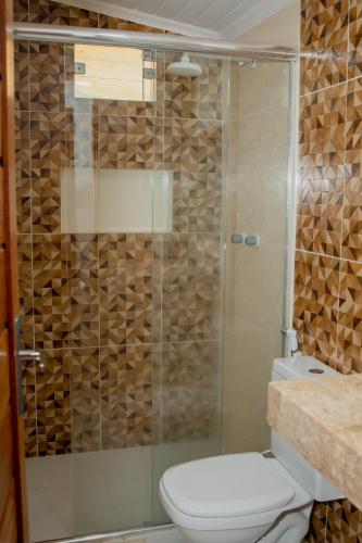 a bathroom with a toilet and a glass shower at Pousada Muiraquitã Parintins in Parintins