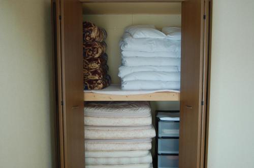 een kast gevuld met gevouwen handdoeken en een stapel handdoeken bij Chalet 別邸しろうま in Hakuba