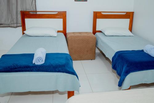 a room with two beds with blue and white sheets at Pousada Muiraquitã Parintins in Parintins