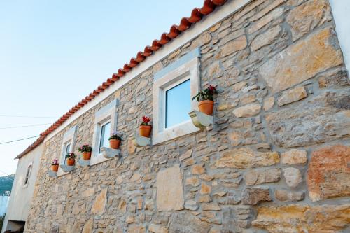 a stone building with windows and potted plants on it at Casa da Boneca in Batalha