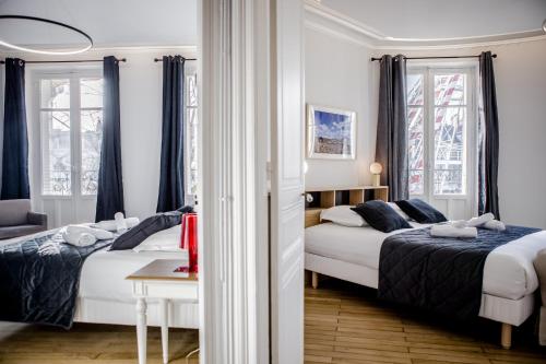 two beds in a room with two windows at La Rotonde - Vue sur Place du Martroi Orléans - Climatisation - 5 pers - Hypercentre in Orléans