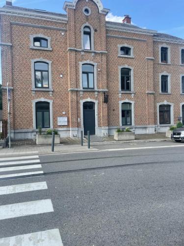 a large brick building with a black door on a street at Logement cosy à Durbuy in Durbuy