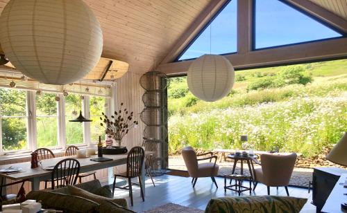 a living room with a table and chairs and windows at Harry's Hut near Welcombe Mouth Beach in Bideford