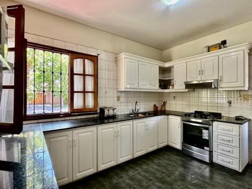 a white kitchen with white cabinets and a window at Hermosa Casa 14 pax Piscina Futbol 5 Chacras in Ciudad Lujan de Cuyo