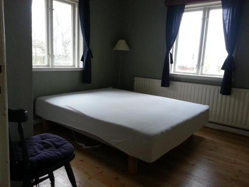 Cama blanca en habitación con 2 ventanas en Hus på Lantgård Viken en Mjöhult