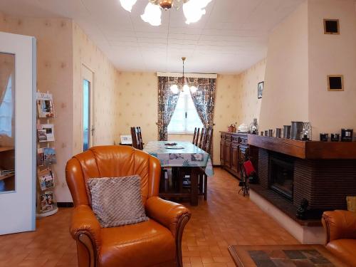 - un salon avec une table et un fauteuil en cuir dans l'établissement Gîte familial avec jardin, billard, vélos, et cheminée, au cœur du parc naturel du Perche. - FR-1-581-91, à Vichères