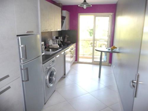 une cuisine avec un réfrigérateur et une table à l'intérieur dans l'établissement Spacieux 3 P Juan les pins, à Antibes