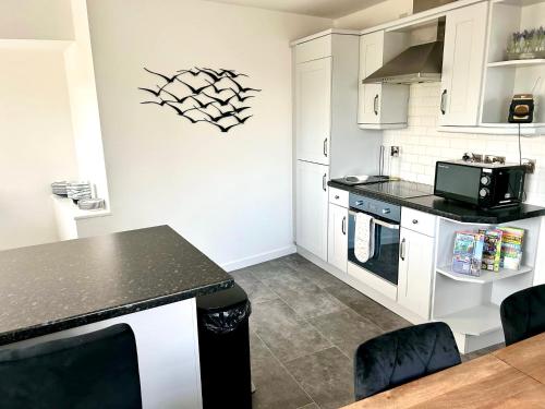 a kitchen with white cabinets and a black counter top at Great location very spacious. Sea and castle view in Marazion