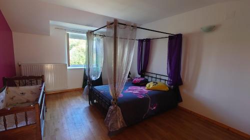 a bedroom with a canopy bed with purple curtains at Gite FABYPHIL in Youx