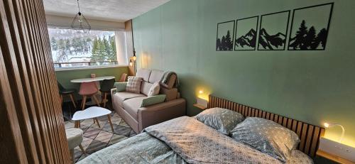 ein Schlafzimmer mit einem Bett, einer Couch und einem Sessel in der Unterkunft LA PETITE LUGE studio sur les pistes centre station Super-Besse in Besse-et-Saint-Anastaise