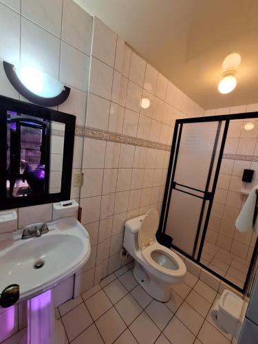 a bathroom with a sink and a toilet and a mirror at Motel Jabaloyas in Tijuana