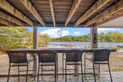 ein Tisch mit Stühlen und Blick auf einen See in der Unterkunft Lake Home with Private Beach and Hot Tub in Ossipee