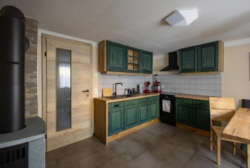 a kitchen with green cabinets and a sink and a table at Heimathaus Hettegger neue gemütliche Ferienwohnung in Grossarl