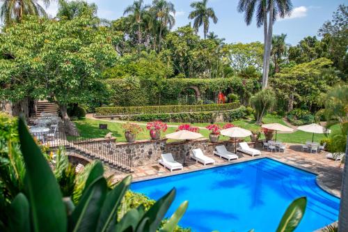 an image of a swimming pool with chairs and umbrellas at Las Mañanitas in Cuernavaca
