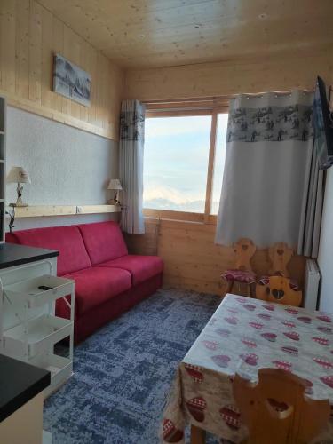 - un salon avec un canapé rouge et une fenêtre dans l'établissement Studio chaleureux à Aime la Plagne 25 m² en montagne, à Aime La Plagne