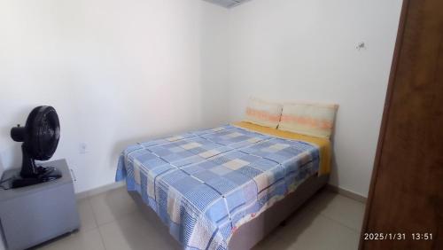 a small bedroom with a bed and a fan at Casa da Praia Capão da Canoa in Capão da Canoa