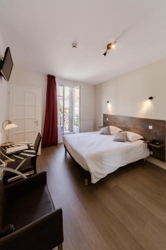 une chambre avec un grand lit blanc et une chaise dans l'établissement LOGIS HOTEL - Le Petit Bellon, à Senlis