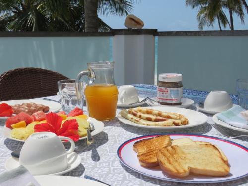 een tafel met toast en sinaasappelsap en een bord brood bij Beachfront Apartments with Private Pool in Kiwengwa