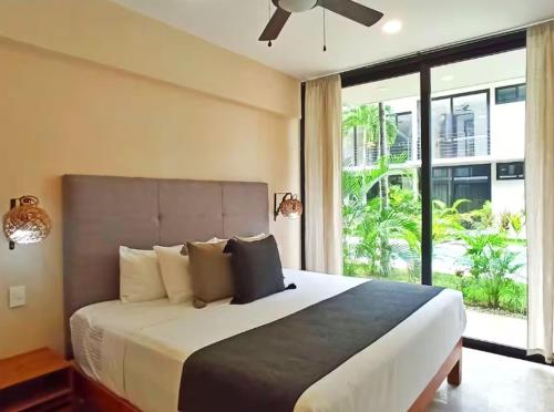 a bedroom with a large bed with a large window at Amena Condo Tulum in Tulum