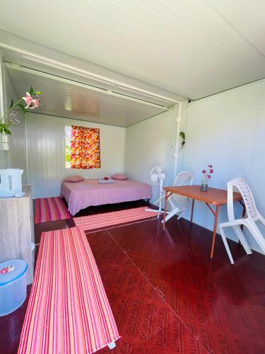 a room with a bed and a table and chairs at Pension Fare Hiro Moorea in Vaianae