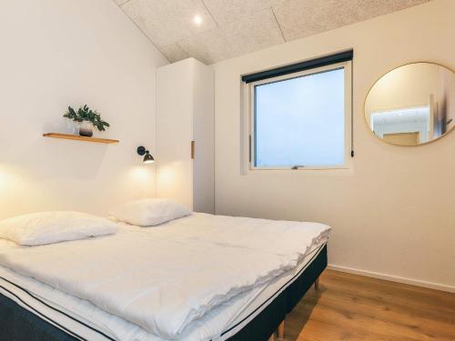 a bedroom with a bed with a mirror and a window at 5 star holiday home in Løkken-By Traum in Løkken
