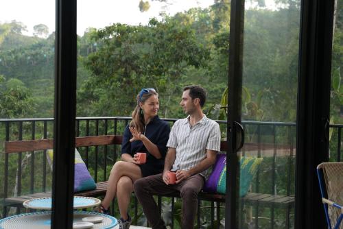 a man and woman sitting on a bench on a porch at Reverie Hotel in Filandia