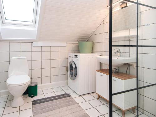 a bathroom with a toilet a sink and a washing machine at 4 star holiday home in Rømø-By Traum in Sønderby