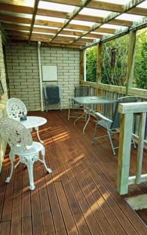 a covered deck with chairs and tables and a table and chairs at Park View 'Home Away From Home' in Feilding